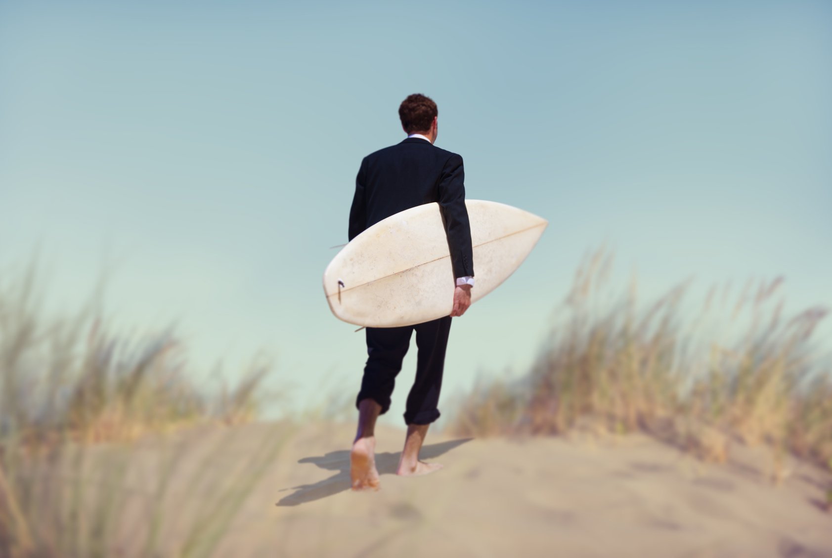 Dieses Bild zeigt einen Mann im Anzug mit einem surfboard unter dem Arm. Dieses Bild zeigt einen Mann im Anzug mit einem surfboard unter dem Arm.